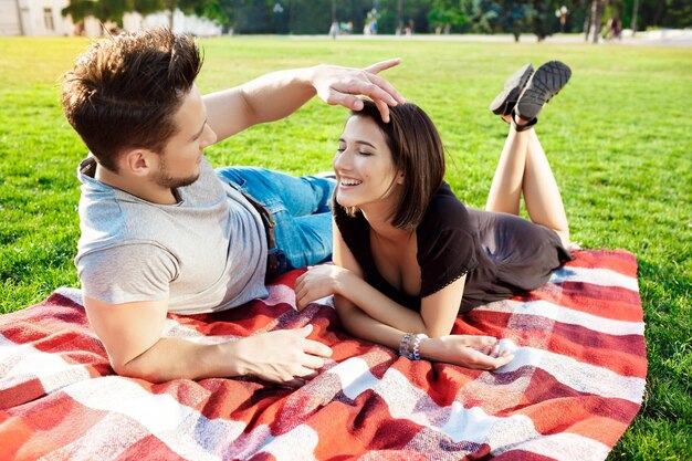 Young beautiful couple smiling resting on picnic in park