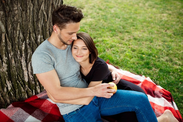 Free photo young beautiful couple smiling, resting on picnic in park.