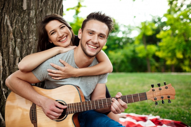 Young beautiful couple smiling, resting on picnic in park.