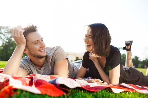 笑みを浮かべて、公園でのピクニックで休んで美しいカップル。