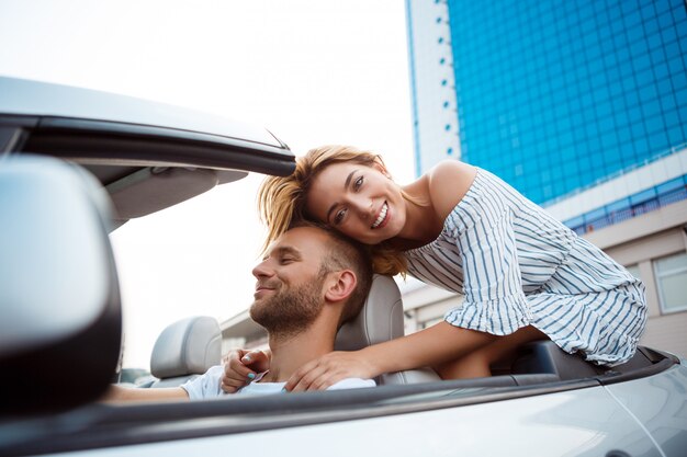 Young beautiful couple smiling, sitting in car near sea.