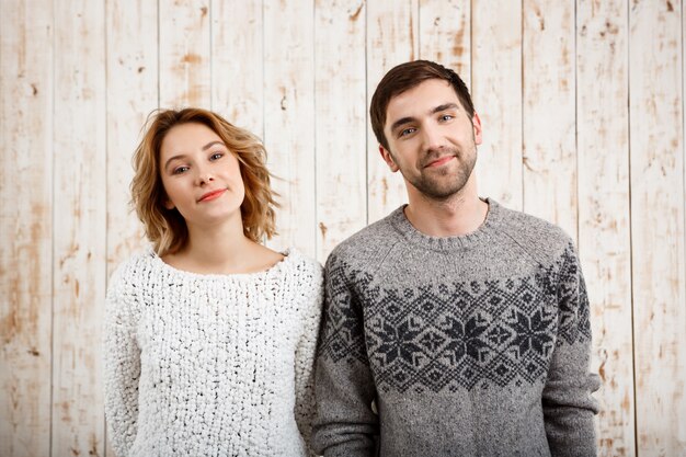 Young beautiful couple  smiling over wooden wall