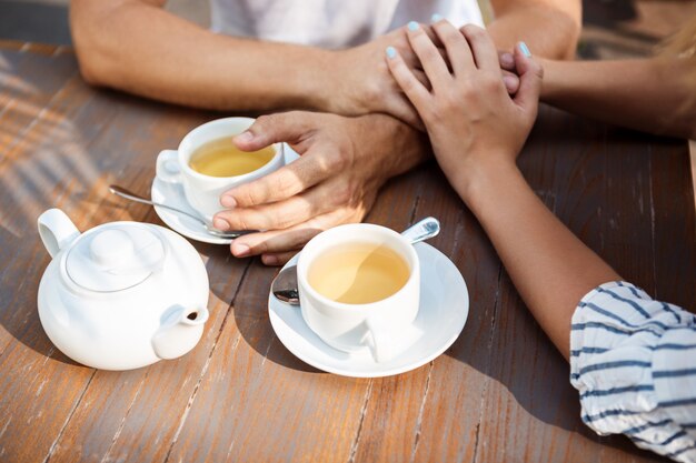 Young beautiful couple speaking, smiling, resting in cafe.