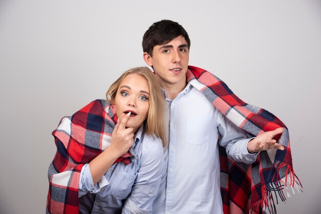 Young beautiful couple standing in a checkered blanket and looking at camera