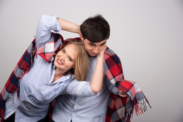 Young beautiful couple standing in a checkered blanket and posing