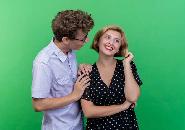 Молодая красивая пара удивила мужчину, глядя на свою любимую девушку, которая широко улыбалась, стоя над зеленой стеной