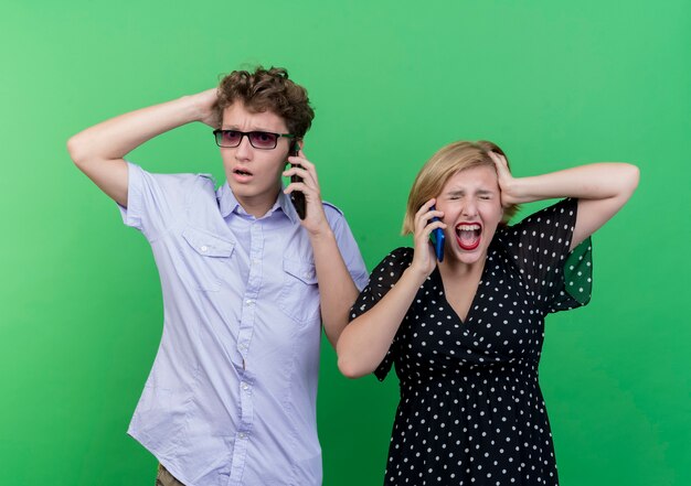 젊은 아름 다운 부부 화가 남자와 녹색 벽 위에 서 휴대 전화에 대 한 얘기 화가 여자
