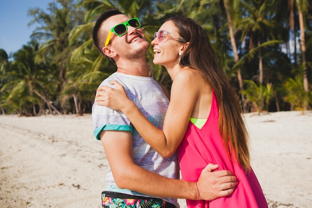 Young beautiful couple walking on tropical beach, thailand, hugging, laughing, sunglasses, having fun, hipster outfit, casual style, honey moon, vacation, summertime, sunny, romantic mood