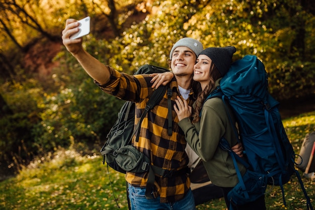 Young beautiful couple with hiking backpacks make selfie during the trekking