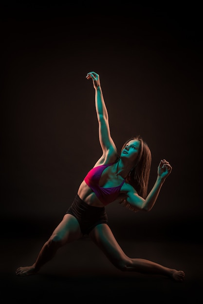 Free photo young beautiful dancer in beige dress dancing on black