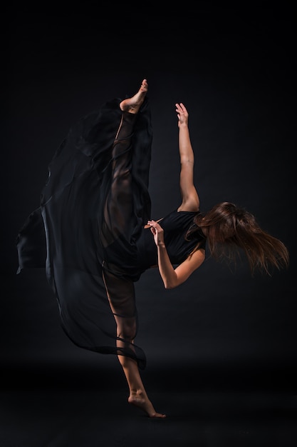 黒の上で踊ってベージュのドレスの若い美しいダンサー