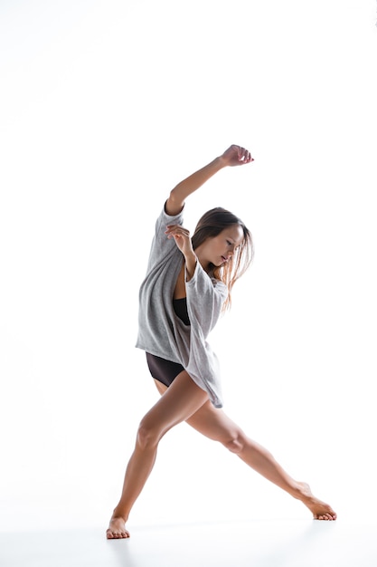 Young beautiful dancer in beige dress dancing on white background