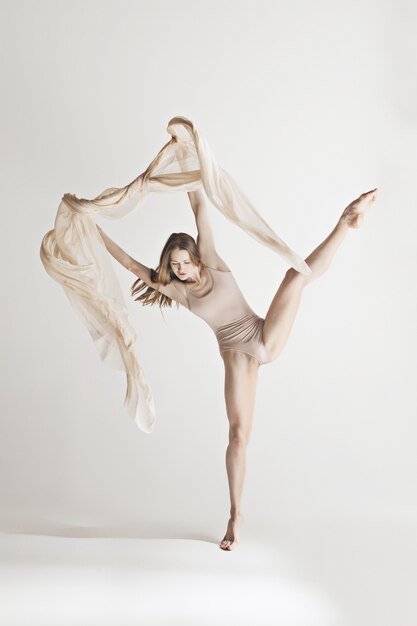 Young beautiful dancer in beige swimsuit dancing