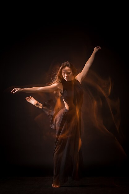 Young beautiful dancer dancing on black wall