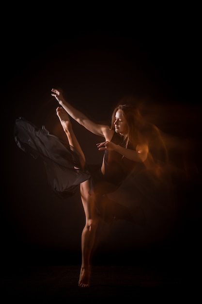 Молодая красивая танцовщица танцует на черной стене