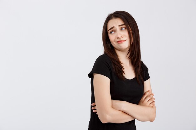 Young beautiful disappointed girl in black t-shirt posing  over white wall