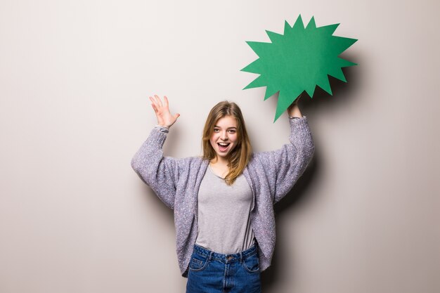 Young beautiful excited teen girl holding a green bubble for text, isolated