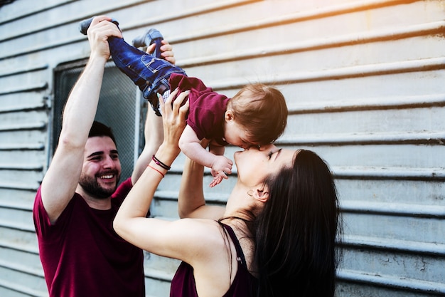 Free photo young beautiful family with child posing on the building