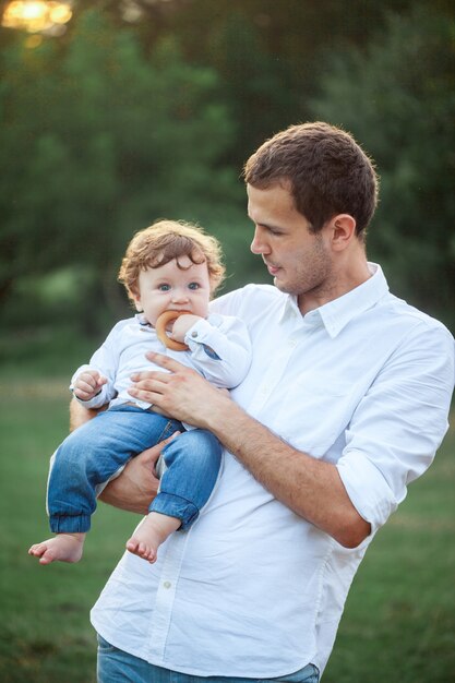 Young beautiful father and little toddler son against green grass