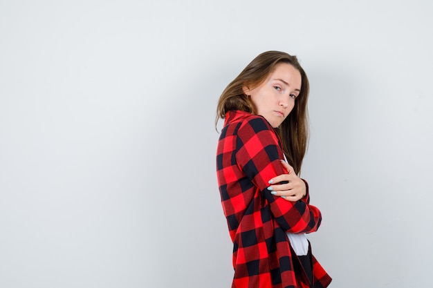 Young beautiful female in casual outfit hugging herself and looking cheerless .