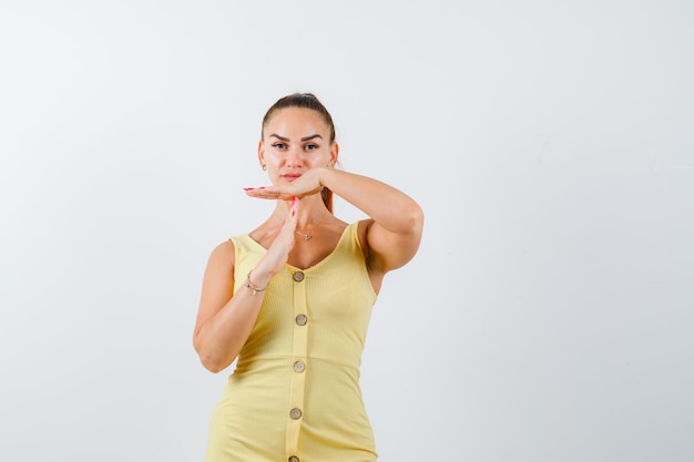 Young beautiful female in dress showing time break gesture and looking confident , front view.