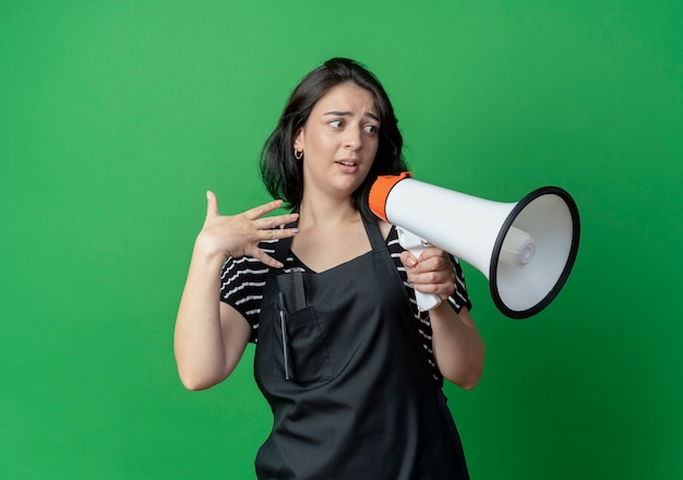 Foto gratuita giovane bella donna parrucchiere in grembiule cercando confuso guardando da parte stressato e nervoso sul verde