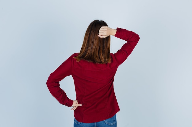 Young beautiful female holding hand behind back in shirt and looking confident