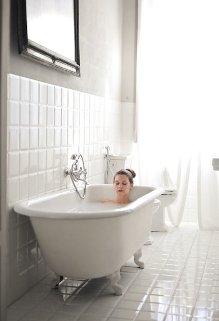 Young beautiful female lying in a bathtub and having a rest