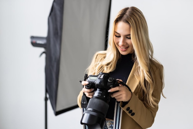 Giovane bella femmina in posa per un servizio fotografico in uno studio che un fotografo sta riprendendo con una fotocamera digitale