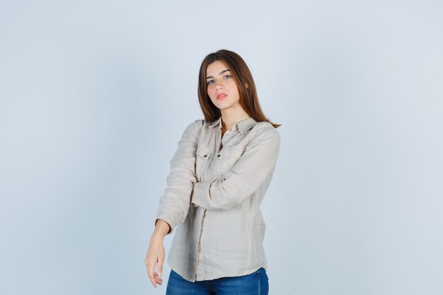 Young beautiful female posing while standing in shirt and looking pensive.