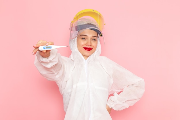 young beautiful female in special white suit holding device on pink