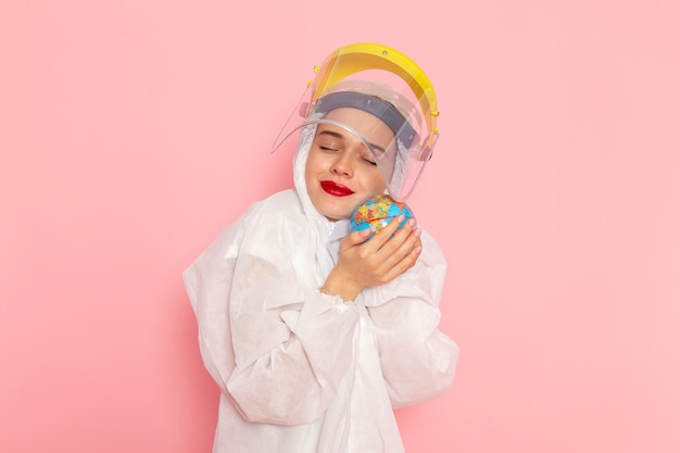 young beautiful female in special white suit holding little globe on pink