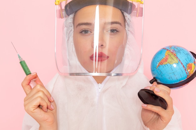 Free photo young beautiful female in special white suit wearing protective helmet holding injection globe on pink