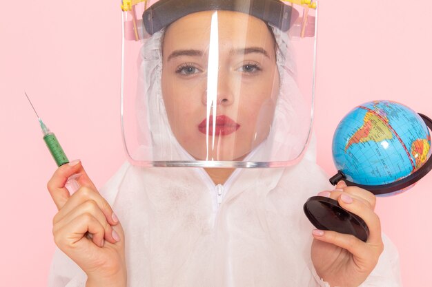 young beautiful female in special white suit wearing protective helmet holding injection globe on pink