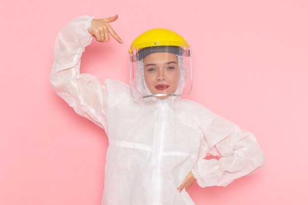 young beautiful female in special white suit and yellow helmet posing on pink