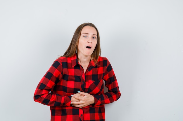 Free photo young beautiful female suffering from stomachache in casual shirt and looking painful , front view.