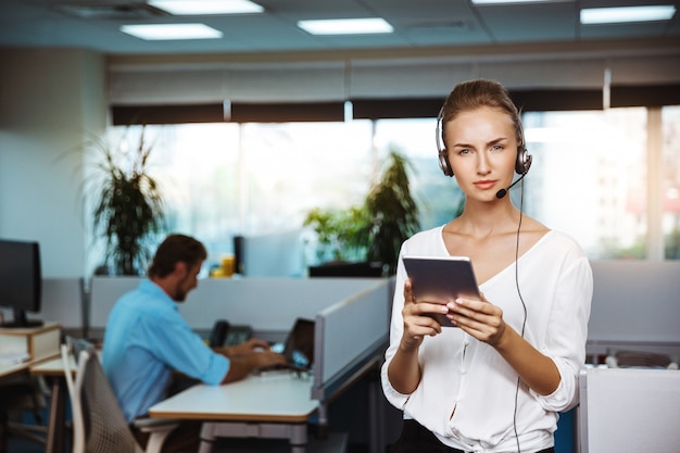 Young beautiful female support phone operator speaking, consulting, over office