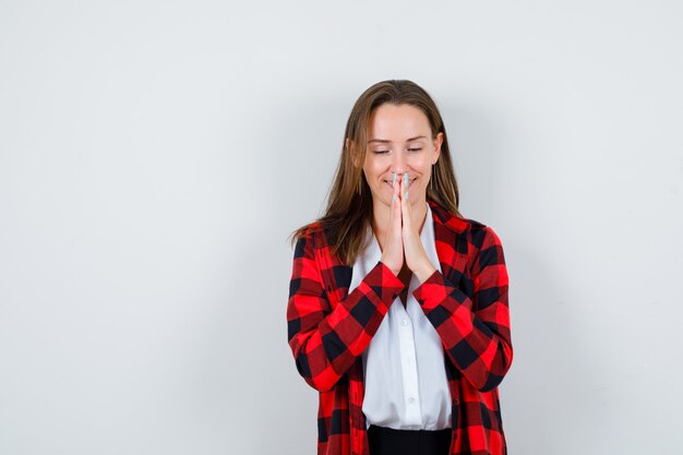 カジュアルな服装でジェスチャーを祈り、希望を持って見える手を持つ若い美しい女性。正面図。