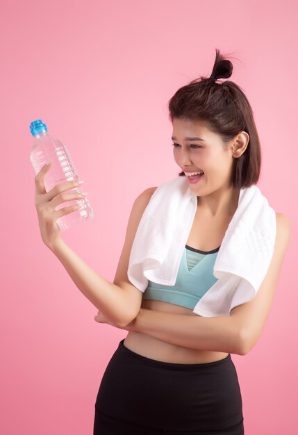 Young beautiful fit woman drinking water after exercise