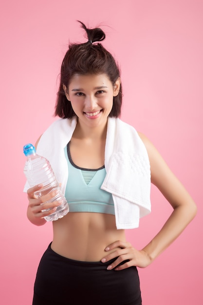 Young beautiful fit woman drinking water after exercise