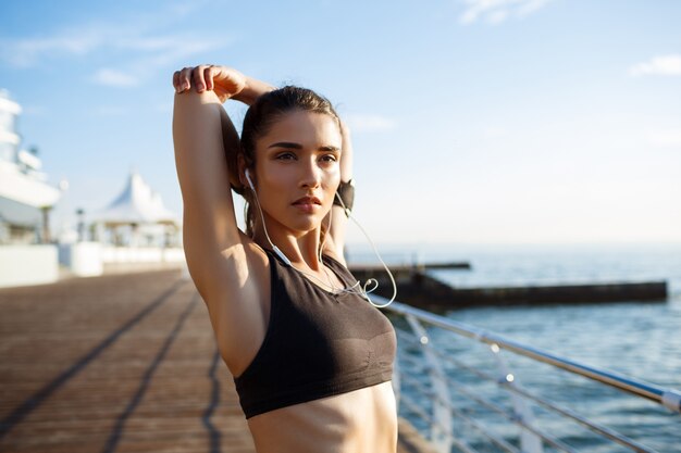  young beautiful fitness girl makes sport exercises with sea coast on wall