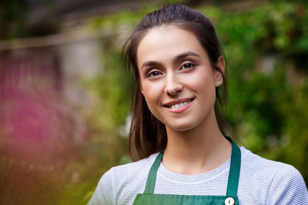 Young beautiful florist posing, smiling among flowers.