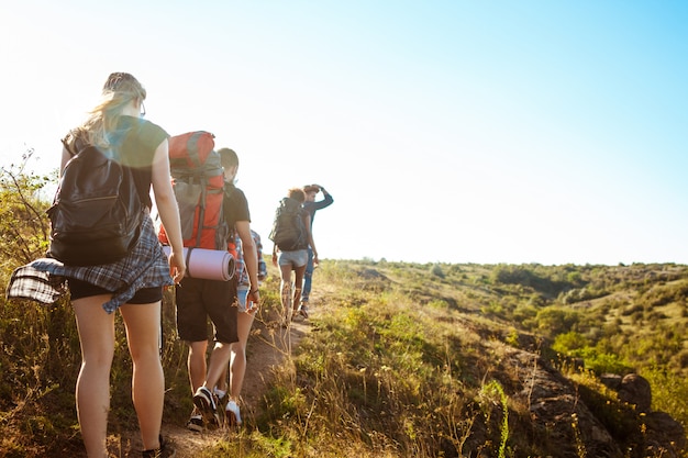 Free photo young beautiful friends travelers with backpacks walking in canyon