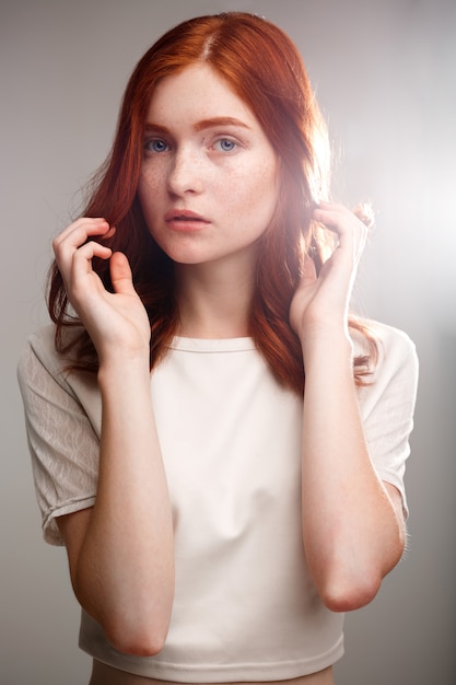 young beautiful ginger girl over gray wall with back light.