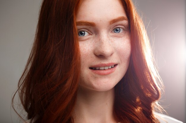 young beautiful ginger girl over gray wall with back light.