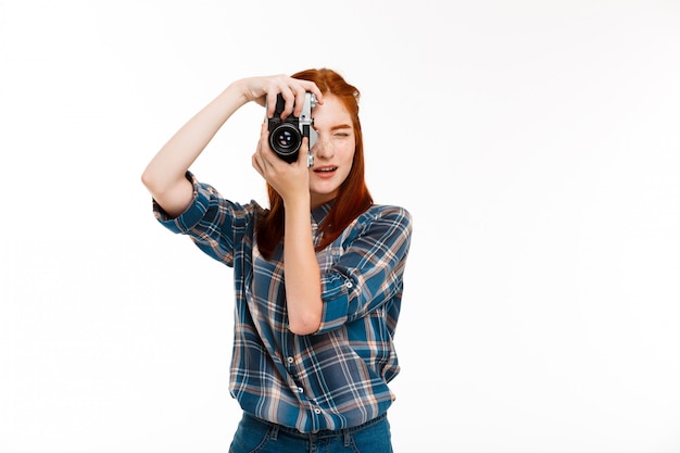 young beautiful ginger photographer over white wall.