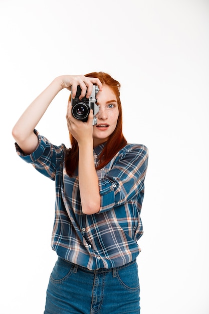 Free photo young beautiful ginger photographer over white wall.