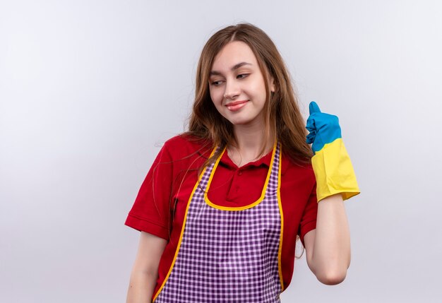 Young beautiful girl in apron and rubber gloves happy and positive clenching fist 