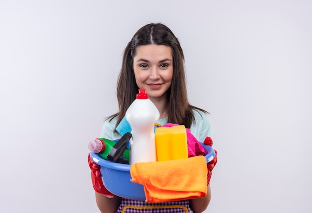 Free photo young beautiful girl in apron and rubber gloves holding basin with cleaning tools smiling confident