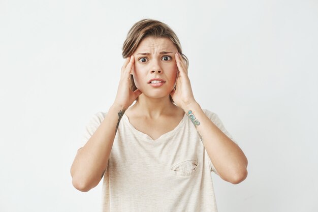 Young beautiful girl ashamed frowning with fingers on temples .